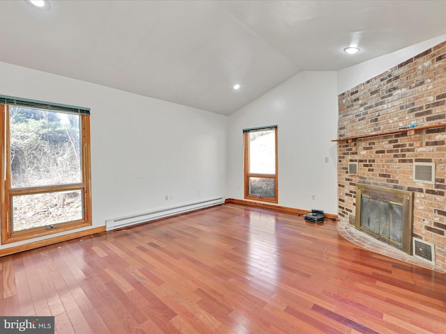 unfurnished living room with vaulted ceiling, plenty of natural light, wood finished floors, and baseboard heating