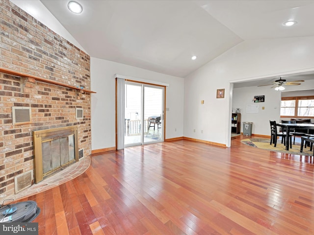 unfurnished living room with light wood finished floors, visible vents, ceiling fan, lofted ceiling, and a fireplace