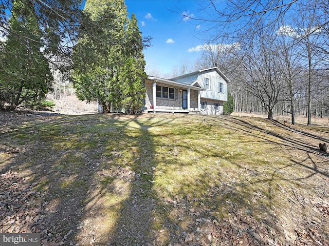 tri-level home featuring brick siding, covered porch, and a front lawn