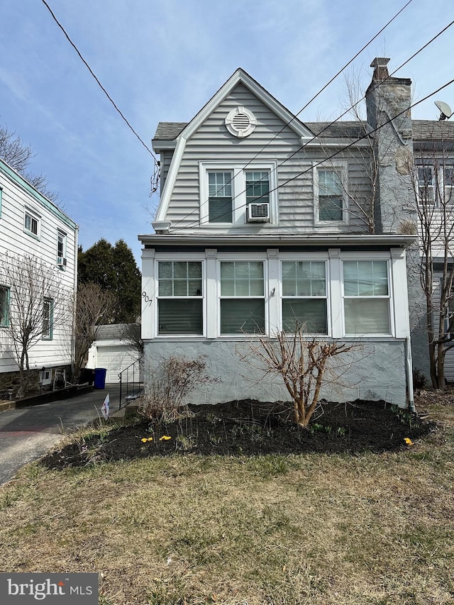 view of front of home with a garage, a gambrel roof, and a chimney