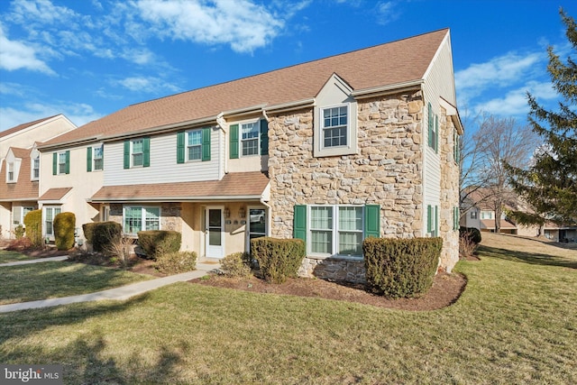 view of front of property with stone siding, a front yard, and a shingled roof