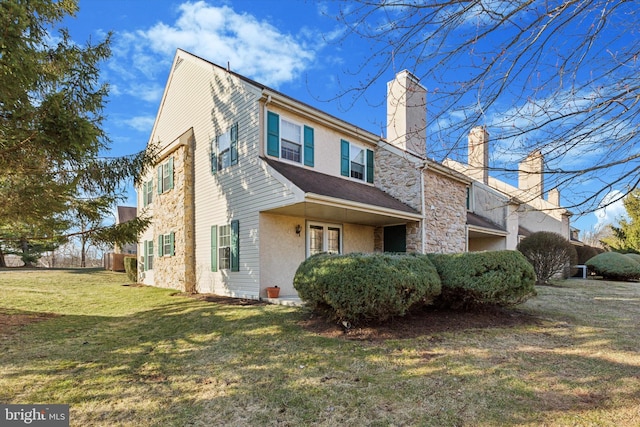 view of home's exterior with a yard, stone siding, and a chimney