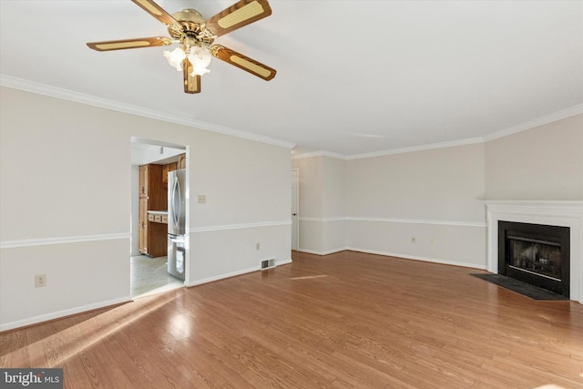 unfurnished living room featuring visible vents, baseboards, a fireplace with flush hearth, ornamental molding, and wood finished floors