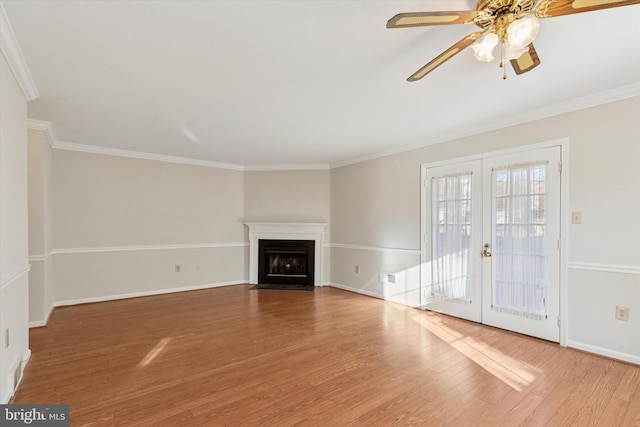 unfurnished living room featuring a fireplace with flush hearth, ornamental molding, french doors, and wood finished floors