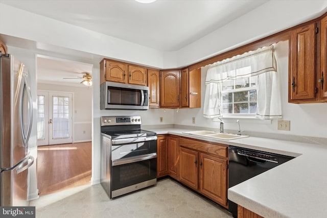 kitchen with light countertops, brown cabinetry, appliances with stainless steel finishes, and a sink