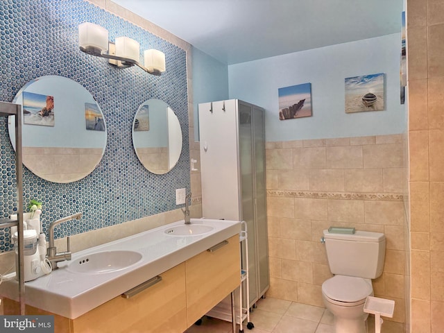 bathroom featuring tile walls, toilet, tile patterned floors, and a sink