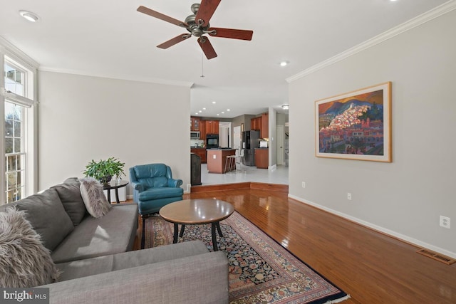 living room with visible vents, ornamental molding, recessed lighting, light wood-style floors, and baseboards