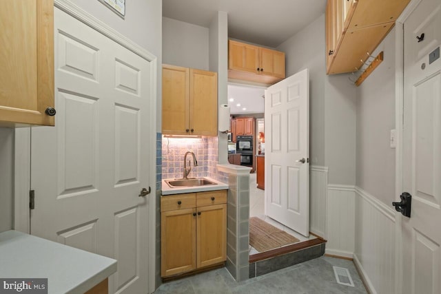 bathroom featuring decorative backsplash, visible vents, a wainscoted wall, and a sink