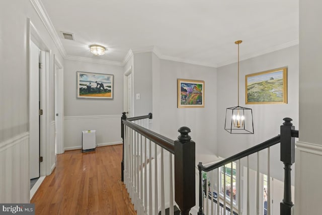 hall featuring an upstairs landing, visible vents, light wood-type flooring, and ornamental molding