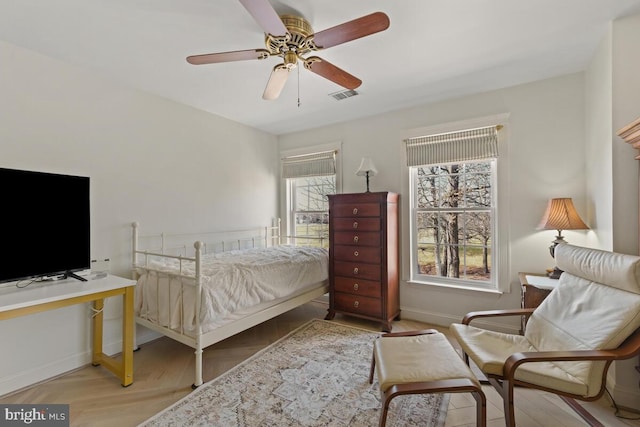 bedroom featuring visible vents, ceiling fan, baseboards, and wood finished floors