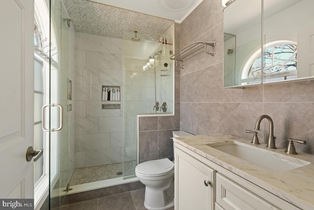 bathroom featuring toilet, tile walls, a shower stall, and tile patterned flooring