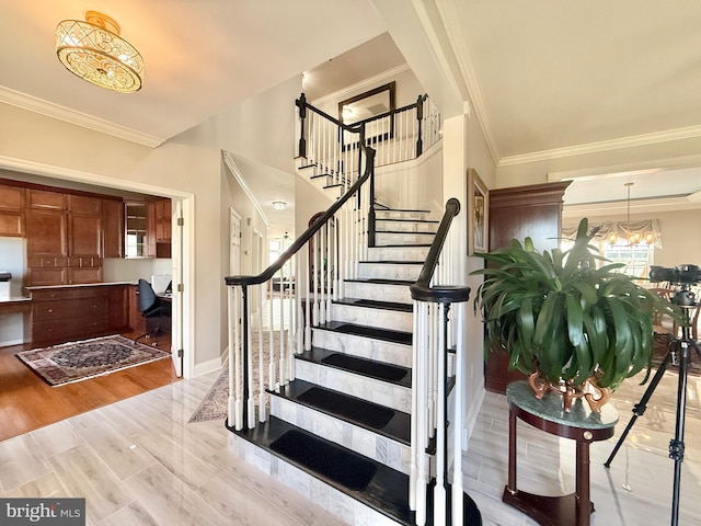 staircase featuring baseboards, a notable chandelier, wood finished floors, and ornamental molding