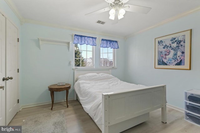 bedroom with crown molding, light wood-style floors, visible vents, and baseboards