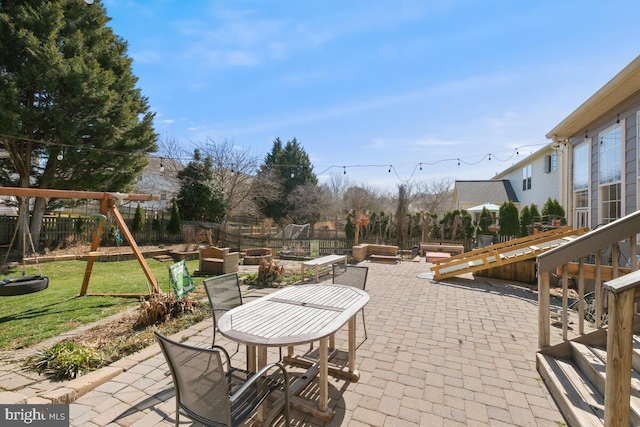 view of patio with outdoor dining area, a fenced backyard, and a playground