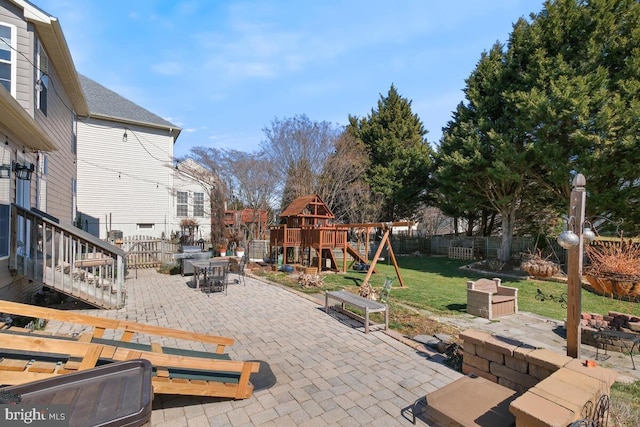 view of patio featuring outdoor dining space, a playground, and a fenced backyard