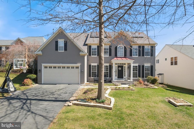 view of front of house with aphalt driveway, roof mounted solar panels, a front lawn, and a garage