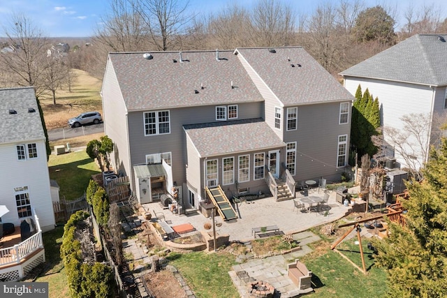 rear view of house with entry steps, roof with shingles, a lawn, a fenced backyard, and a patio area