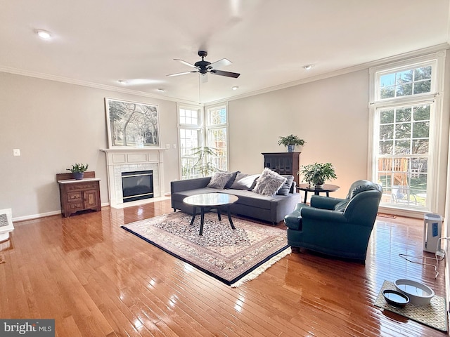 living area featuring light wood-style flooring, a fireplace with flush hearth, baseboards, and ornamental molding