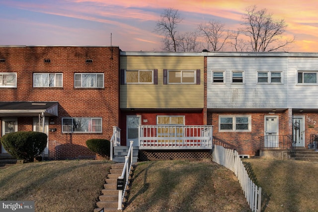 view of property featuring brick siding, a front yard, and fence