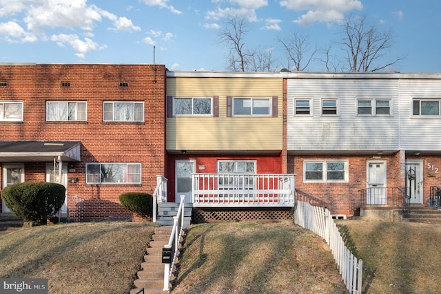 view of property with brick siding, a front yard, and fence