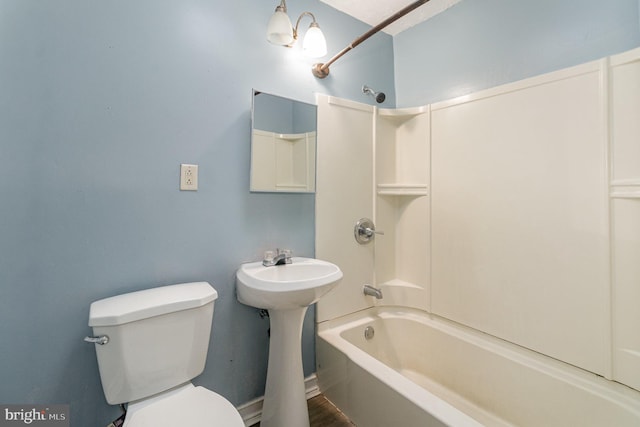 bathroom featuring tub / shower combination, toilet, and a sink