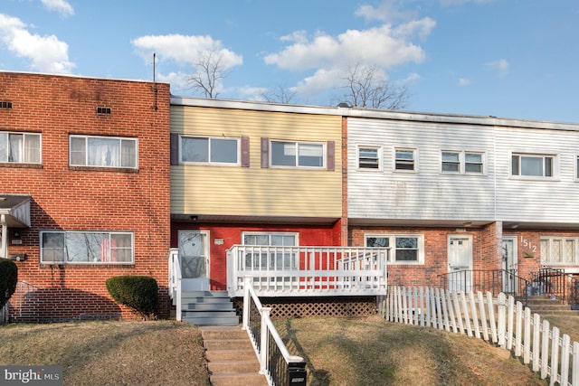 rear view of property featuring fence and brick siding