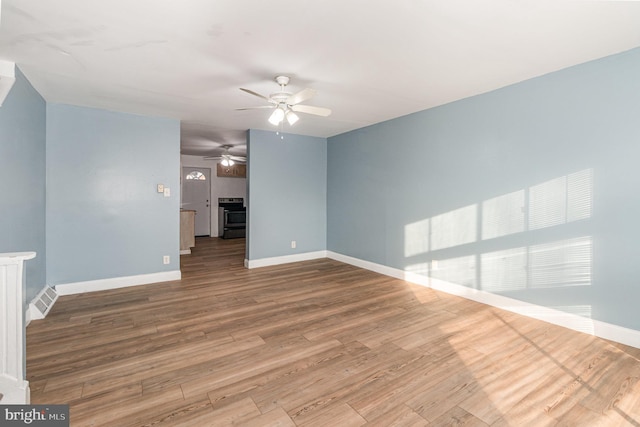 unfurnished living room featuring visible vents, a ceiling fan, baseboards, and wood finished floors