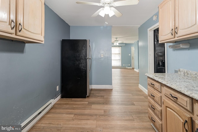 kitchen with a baseboard heating unit, light brown cabinets, light wood-style floors, and freestanding refrigerator