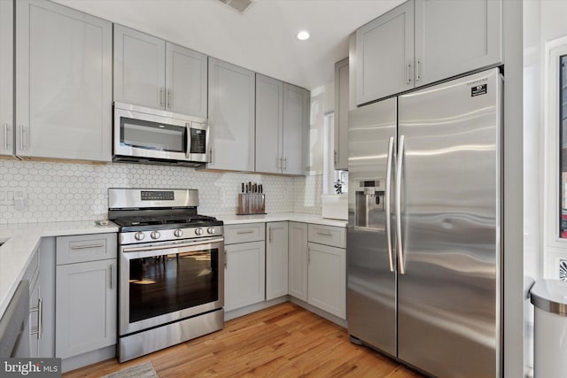 kitchen with decorative backsplash, light wood-style flooring, appliances with stainless steel finishes, and gray cabinetry