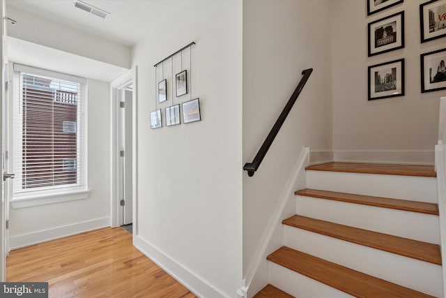 staircase featuring visible vents, baseboards, and wood finished floors