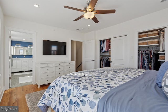 bedroom featuring visible vents, multiple closets, recessed lighting, light wood-style flooring, and ensuite bathroom