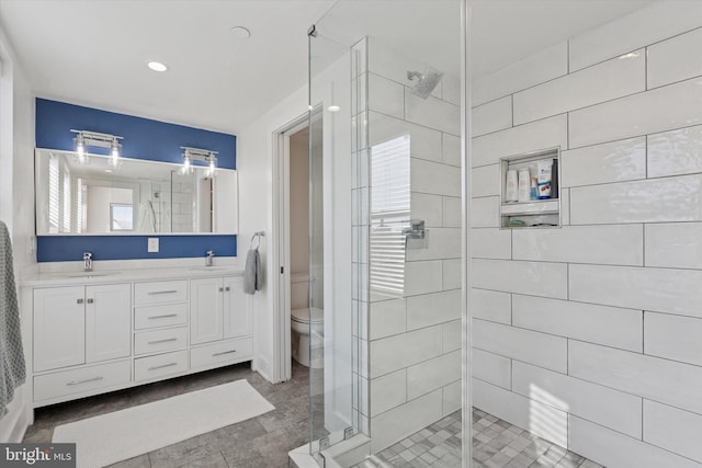 full bathroom featuring a sink, toilet, double vanity, and a shower stall