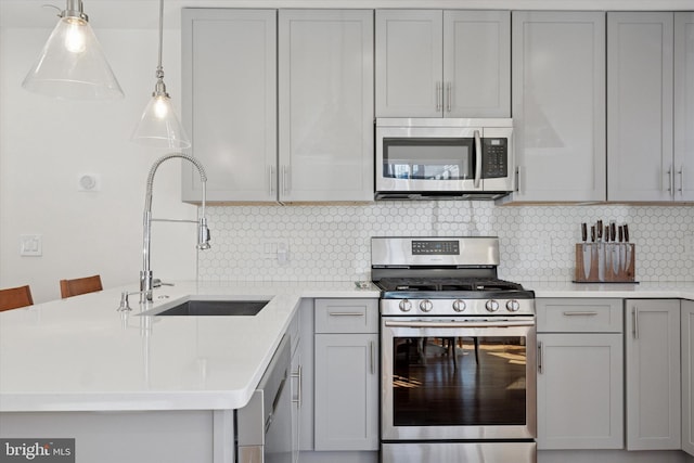 kitchen featuring gray cabinets, a sink, appliances with stainless steel finishes, a peninsula, and light countertops