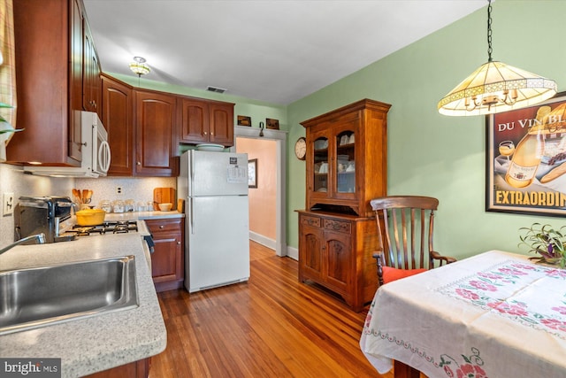 kitchen with white appliances, wood finished floors, light countertops, and a sink