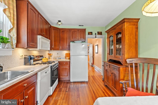 kitchen with visible vents, backsplash, light countertops, light wood-style floors, and white appliances