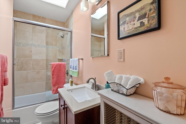 bathroom with shower / bath combination with glass door, a skylight, vanity, and toilet