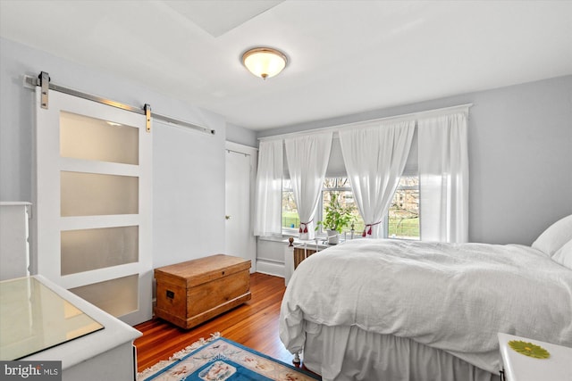 bedroom featuring a barn door and wood finished floors