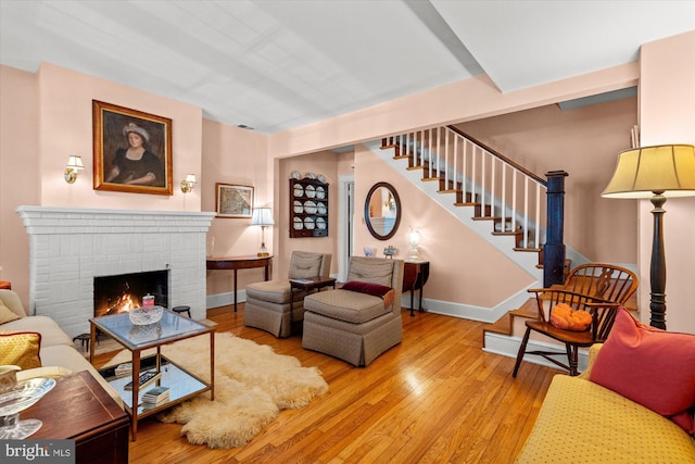 living room with stairs, a fireplace, baseboards, and wood-type flooring