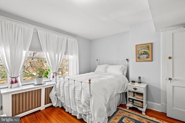 bedroom featuring radiator heating unit, wood finished floors, and baseboards