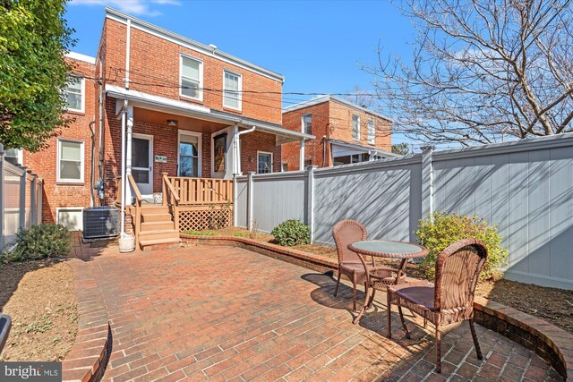 rear view of property featuring brick siding, central AC unit, a patio area, and fence