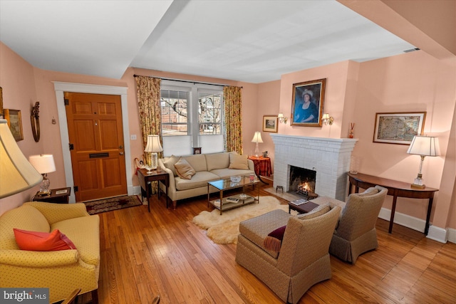 living room featuring baseboards, wood-type flooring, visible vents, and a fireplace