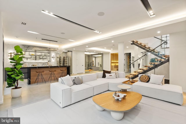 living room with recessed lighting, visible vents, wet bar, and stairs