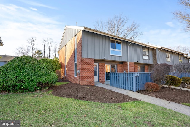 rear view of house with brick siding and a yard