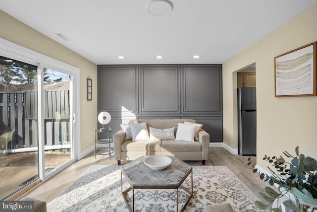 living room featuring light wood finished floors, visible vents, recessed lighting, and baseboards