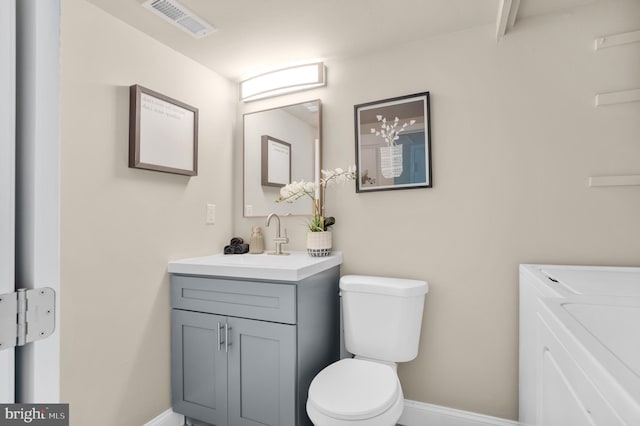 bathroom with vanity, visible vents, baseboards, toilet, and washing machine and dryer