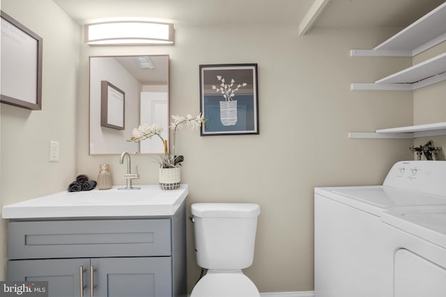 bathroom with washer and dryer, toilet, and vanity