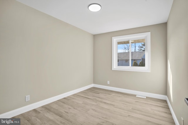 spare room featuring light wood-style flooring, visible vents, and baseboards