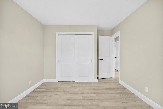 unfurnished bedroom with a closet, light wood-style floors, and baseboards