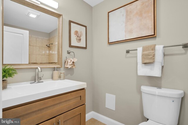 bathroom featuring toilet, vanity, and baseboards