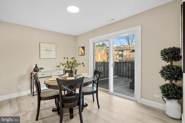 dining room featuring visible vents, light wood-type flooring, and baseboards